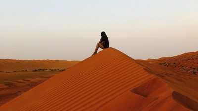 Gilman recipient Tahreem Alam sits atop a dune in the Ash-Sharqiyah desert of Oman.